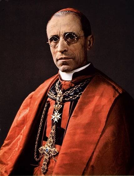 A photograph of Pope Pius XII sitting in red papal wear