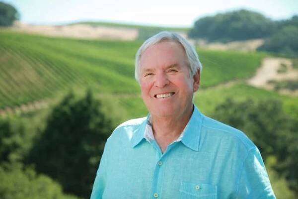 Bill Foley smiling in front of a Foley Family Wine vineyard