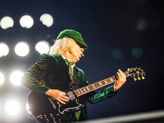 Angus Young pictured in his famous cap and suit get-up, with an SG in hand.