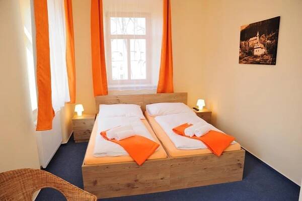 a bedroom with a bed with orange pillows on it at Hotel Praha Potštejn in Potštejn