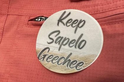 FILE - A sticker saying "Keep Sapelo Geechee" is worn on the shirt of George Grovner, a resident of the Hogg Hummock community on Sapelo Island, during a meeting of McIntosh County commissioners, Sept. 12, 2023, in Darien, Ga. On Thursday, Oct. 12, Black residents of the tiny island enclave founded by their enslaved ancestors off the Georgia coast filed suit seeking to halt a new zoning law that they say will raise taxes and force them to sell their homes in one of the South's last surviving Gullah-Geechee communities. (AP Photo/Ross Bynum, File)