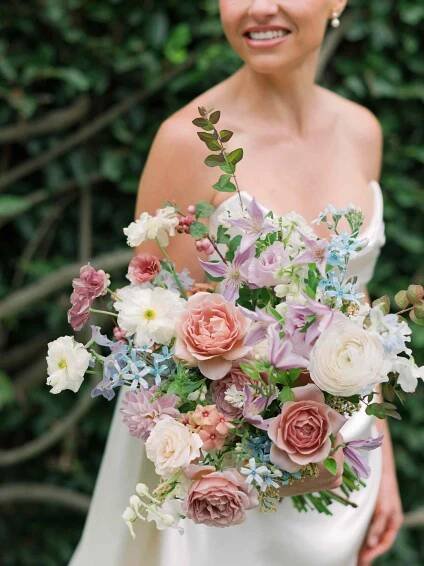 Close up of bride in wedding dress holding colorful bouquet 