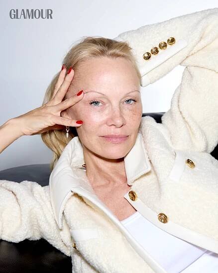 a woman with red nail polish holding her hand up to her face and looking at the camera