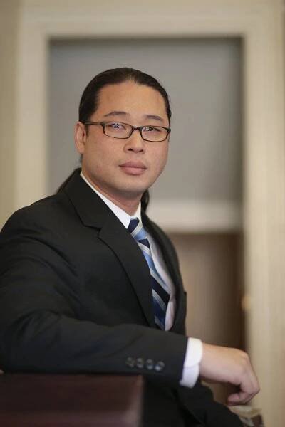A man in a suit and tie is leaning on a table.