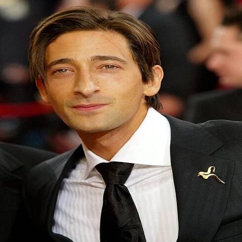 Man in a dark suit and tie on a red carpet
