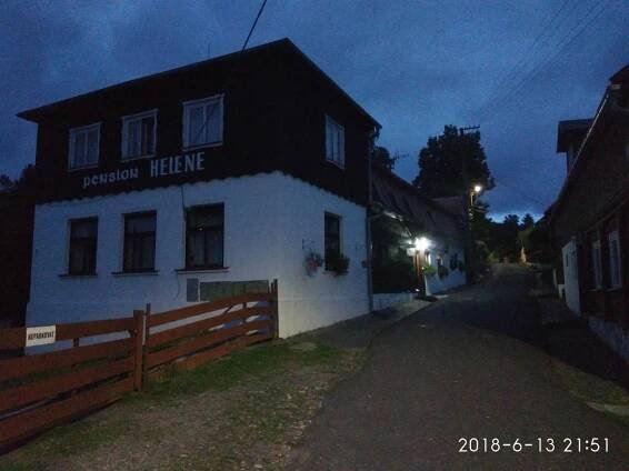 a white building with a black roof on a street at Pension Helene s mini pivovarem in Kytlice