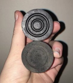 a picture of the bottoms of two cane tips. a new one that is shiny black rubber with very distinct and fairly deep spiral treads, and an old worn down one with barely visible remnants of spiral treads.