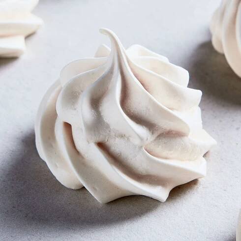 Five vanilla meringue cookies on a kitchen countertop.