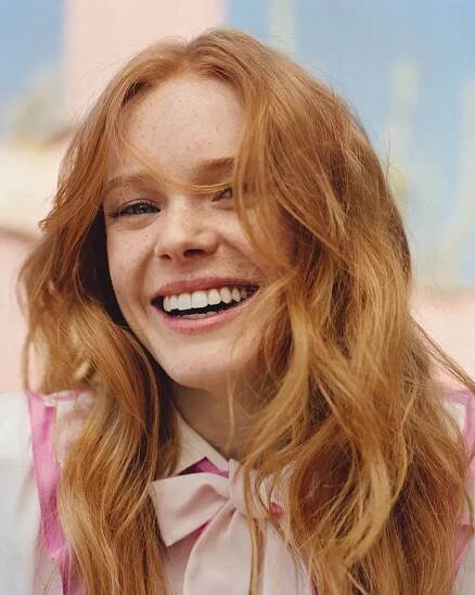 a close up of a person with long red hair wearing a shirt and bow tie