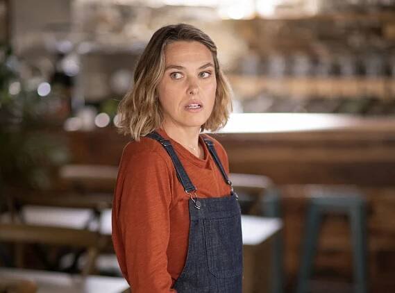 Sally Bretton as Martha Lloyd in Beyond Paradise, standing in her caf&eacute; which can be seen out of focus behind her