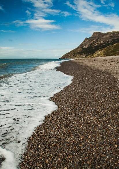A shingly beach with the tide coming in.