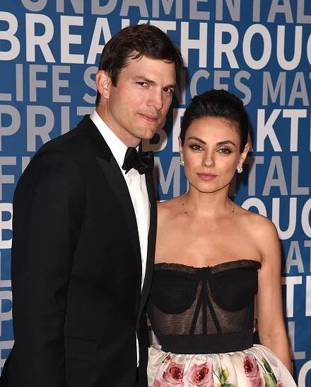 Ashton Kutcher in a black tuxedo with Mila Kunis in a strapless black dress