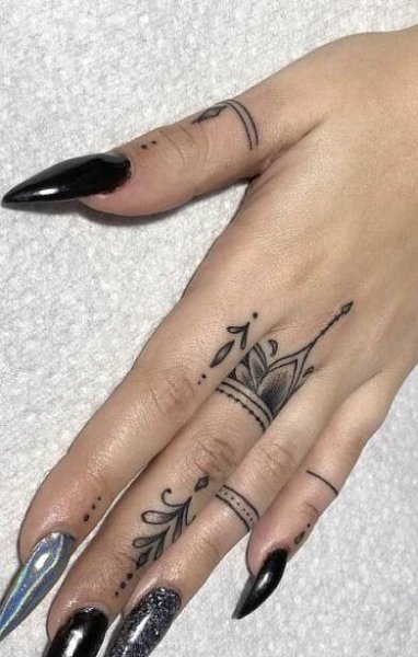 a woman's hand with black nail polish and tattoos on her left ring finger
