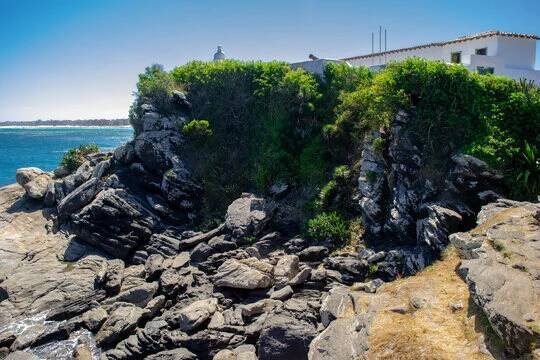 Behind the Praia do Forte fort, with many rocks with fungi, vegetation and part of the fort showing. Cabo Frio, Rio de Janeiro, Brazil.