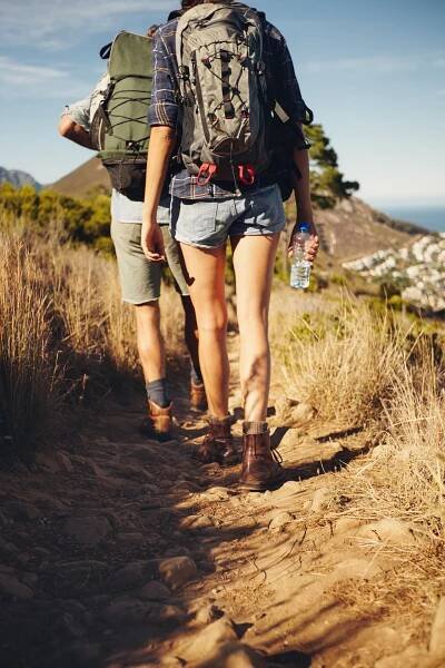 A man and a woman are hiking down a dirt path.