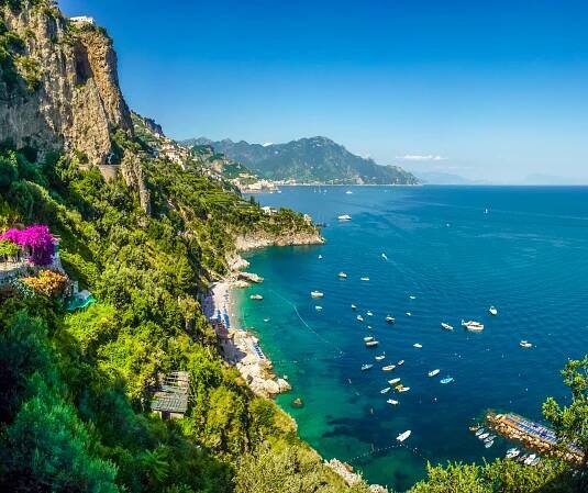 A view of a cliff overlooking a body of water with boats in it.