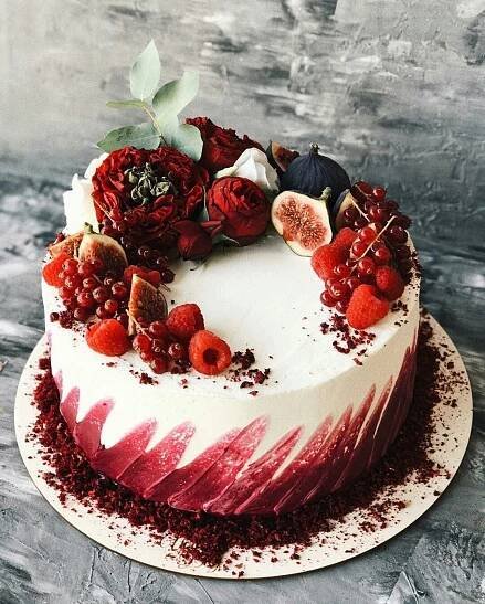 a white cake with red frosting and fresh fruit on top