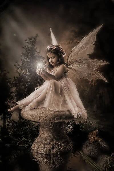 a little fairy sitting on top of a stone statue holding a light bulb in her hand