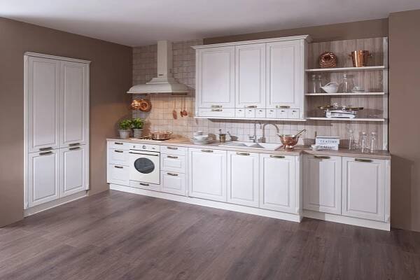 a kitchen with white cabinets and wood flooring in the middle of an empty room
