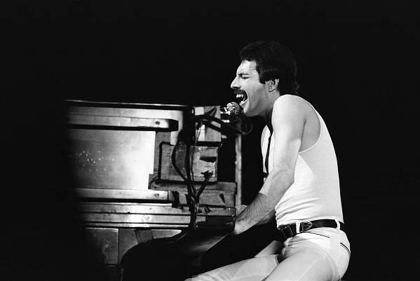 A black and white photo of Freddie Mercury performing on stage