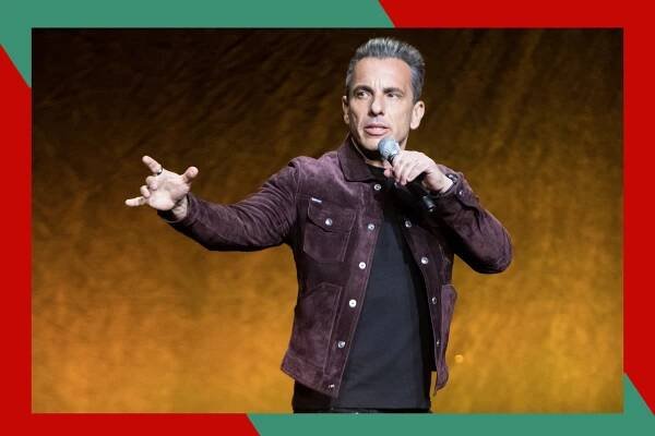 Sebastian Maniscalco gestures toward the crowd while performing onstage.