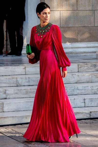 Eine der schönsten Frauen der Hochzeit von Nina Flohr und Prinz Philippos: Alessandra de Osma wählt ein fließendes Kleid mit plissierten Ärmeln und Rock in einem kräftigen Beerenton und sieht darin einfach atemberaubend schön aus. Besonderer Eyecatcher: grüne Stein-Applikationen am Dekolleté sowie die darauf farblich abgestimmte Clutch. Besser geht es nicht.