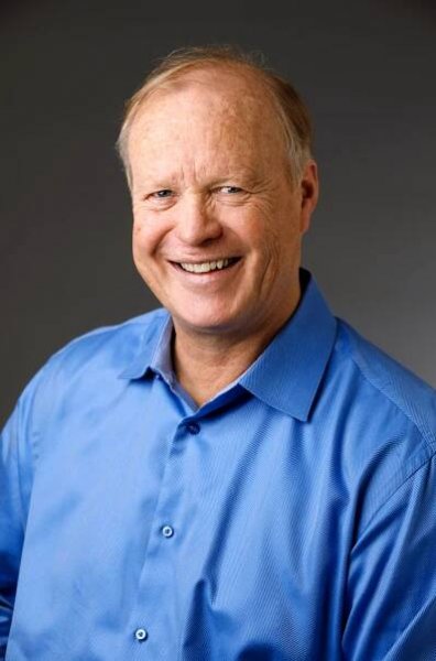 Smiling man in a blue shirt against a plain background