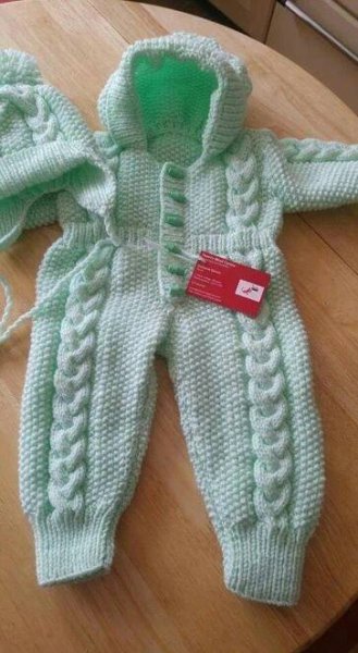 a baby's knitted snowsuit and hat sitting on top of a wooden table
