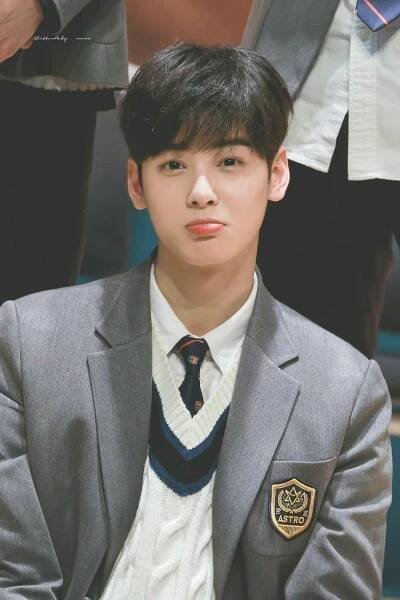a young man wearing a suit and tie sitting in front of other men's suits