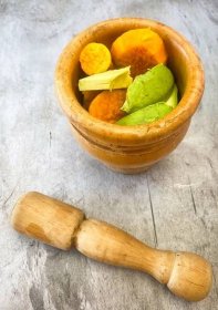 Ingredients for carrot avocado puree in wooden mortar with pestle on grey background