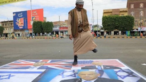 A supporter of Yemen's Huthi movement steps on images of Israeli and western flags and leaders as he takes part in a pro-Palestinian rally in Sanaa on February 8, 2024, amid the ongoing conflict in the Gaza Strip between Israel and the Palestinian militant group Hamas.