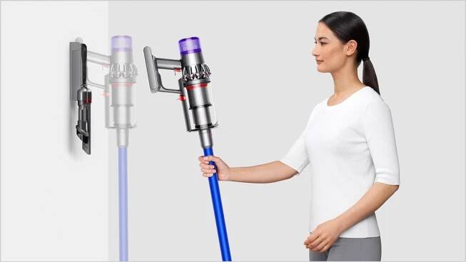 Mladá žena umisťuje tyčový vysavač Dyson V11 Advanced pomocí držáku na zeď_02