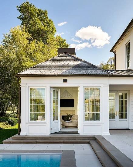 A serene poolside retreat with classic architecture, inviting double doors, and lush greenery in the background.