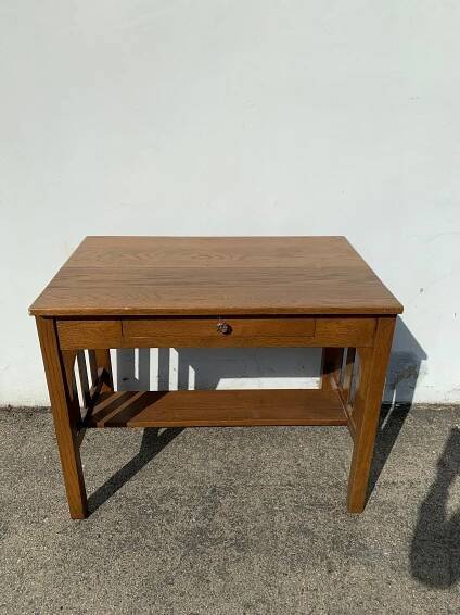 a wooden table sitting on top of a cement floor next to a white stucco wall
