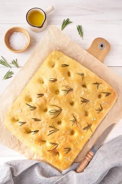baked rosemary focaccia bread resting on a board