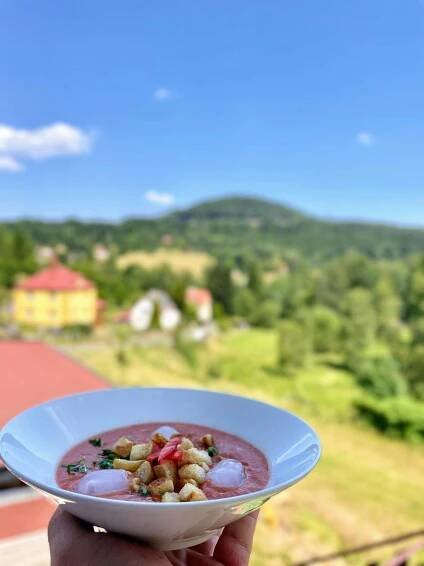 a person holding a bowl of food with a mountain in the background at Pension Helene s mini pivovarem in Kytlice
