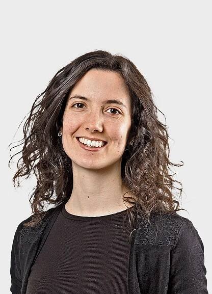 Portrait of a smiling woman with curly brown hair.