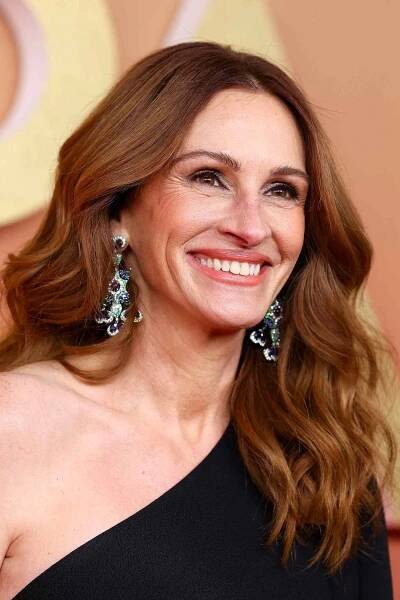Julia Roberts with red-brown, middle-parted hair, dangly earrings, and a black, one-shoulder dress