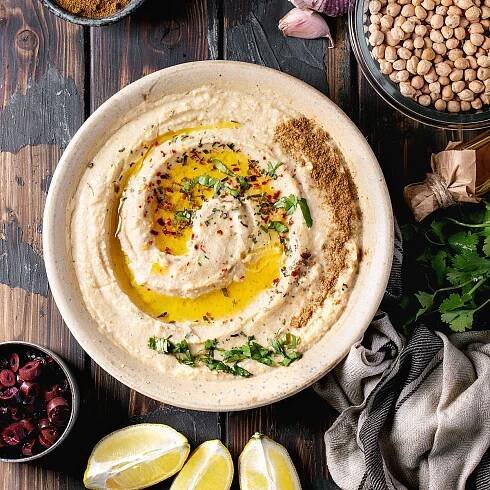 A bowl of hummus on a wood table.