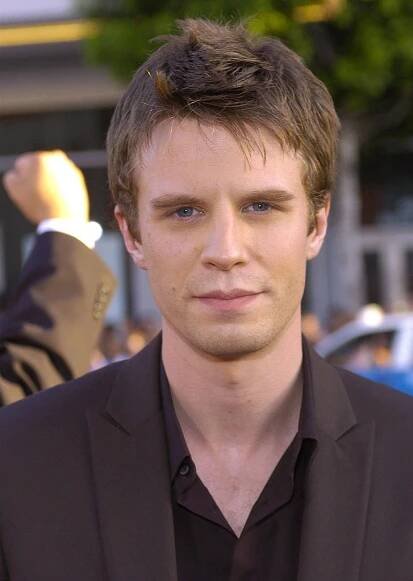 he's got shorter messy hair and a clean-shaven face