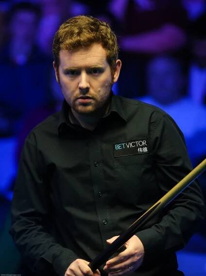 a man with a bet victor shirt holds a cue