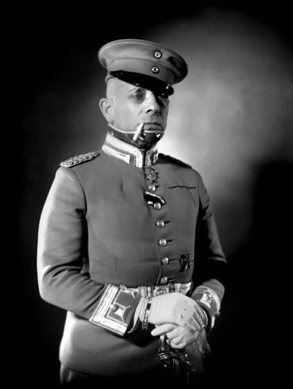 Erich von Stroheim, dans le rôle de Rauffenstein. Il est en uniforme militaire, avec des gants, une casquette (qu'il porte de travers, pour ressembler plus à un méchant) et une cigarette. Il se tient très droit et a l'air sévère. Le bas de son visage est recouvert d'une pièce métallique, suite, probablement, à une blessure de guerre. C'est peut-être ce détail qui a inspiré à Araki l'idée que Stroheim devienne un cyborg dans son manga.
