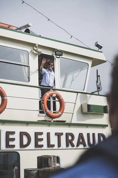 Kapitein Otto Strasser zwaait vanaf zijn boot Edeltraut op de Chiemsee
