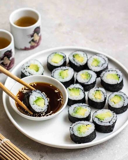 Dipping a piece of avocado maki in soy sauce.