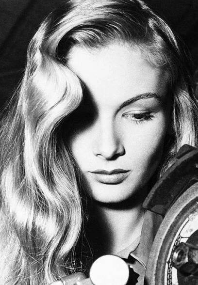 a black and white photo of a woman with long hair holding a clock in her hand