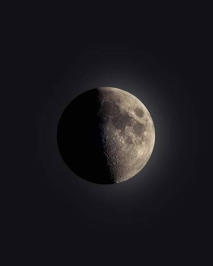 A half moon is seen in the dark sky