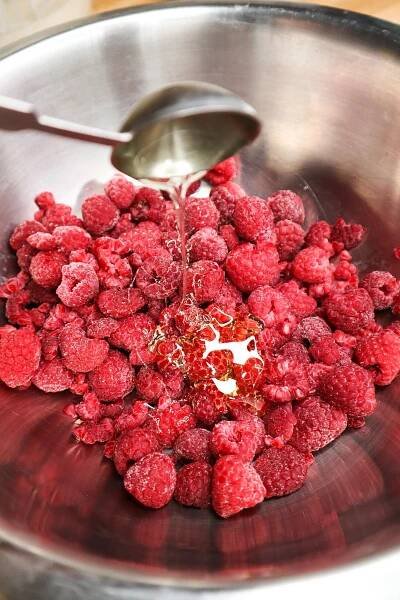Raspberries in a bowl pouring honey 
