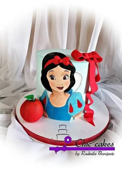 there is a cake that looks like snow white and the red apple sits on top