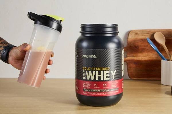 Person holding Optimum Nutrition Gold Standard 100% Whey Protein Powder