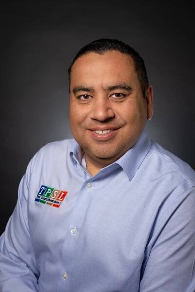 A man in a blue shirt is smiling for the camera.